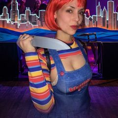 DJ Supernatural (Dannielle DeWaal) in her red-haired costume holding a prop knife